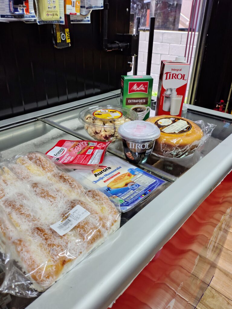 Balcao com produtos do mercado autonomo Bitmarket: pao de queijo, presunto, queijo, cafe, leite e bolo